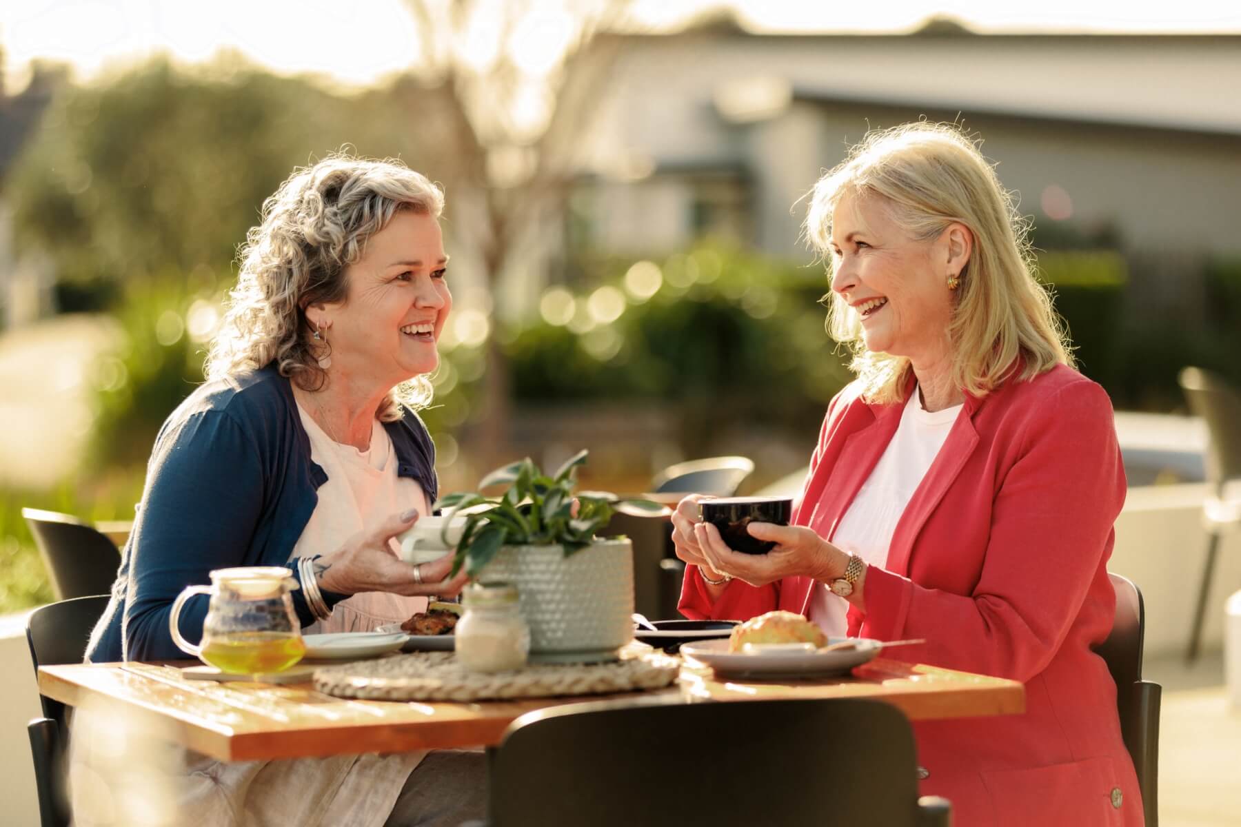 Two women enjoying tea and coffee over conversation outdoors at Paragon Eatery in Olive Estate Lifestyle Village.
