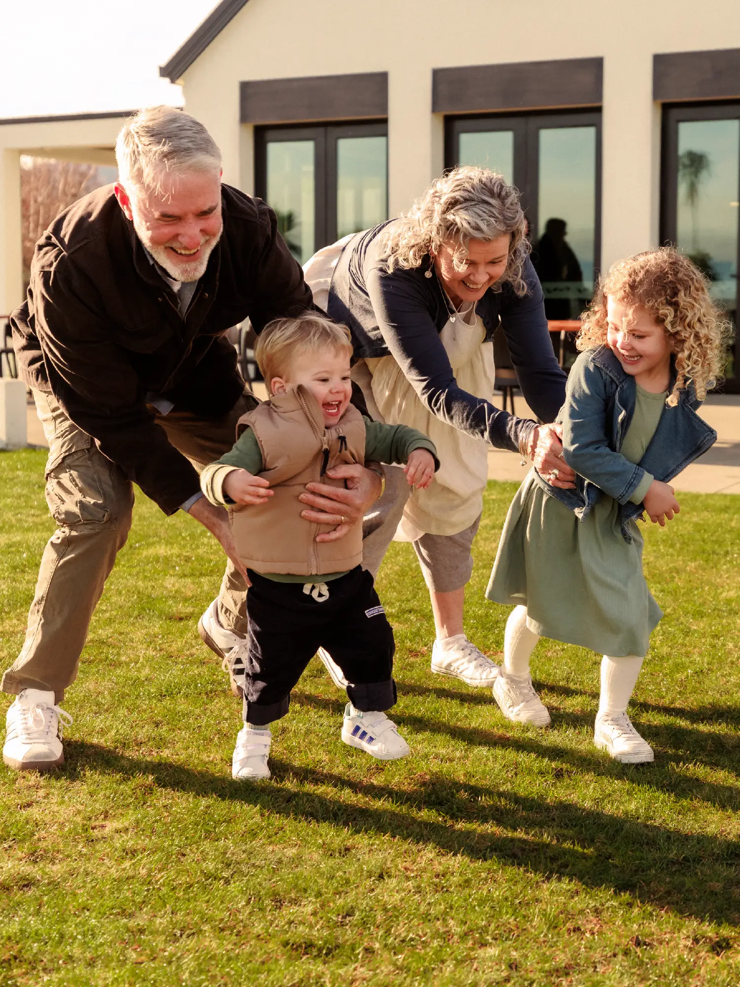 Grandparents playing outdoors on the lawn with their young grandchildren at Olive Estate Lifestyle Village.