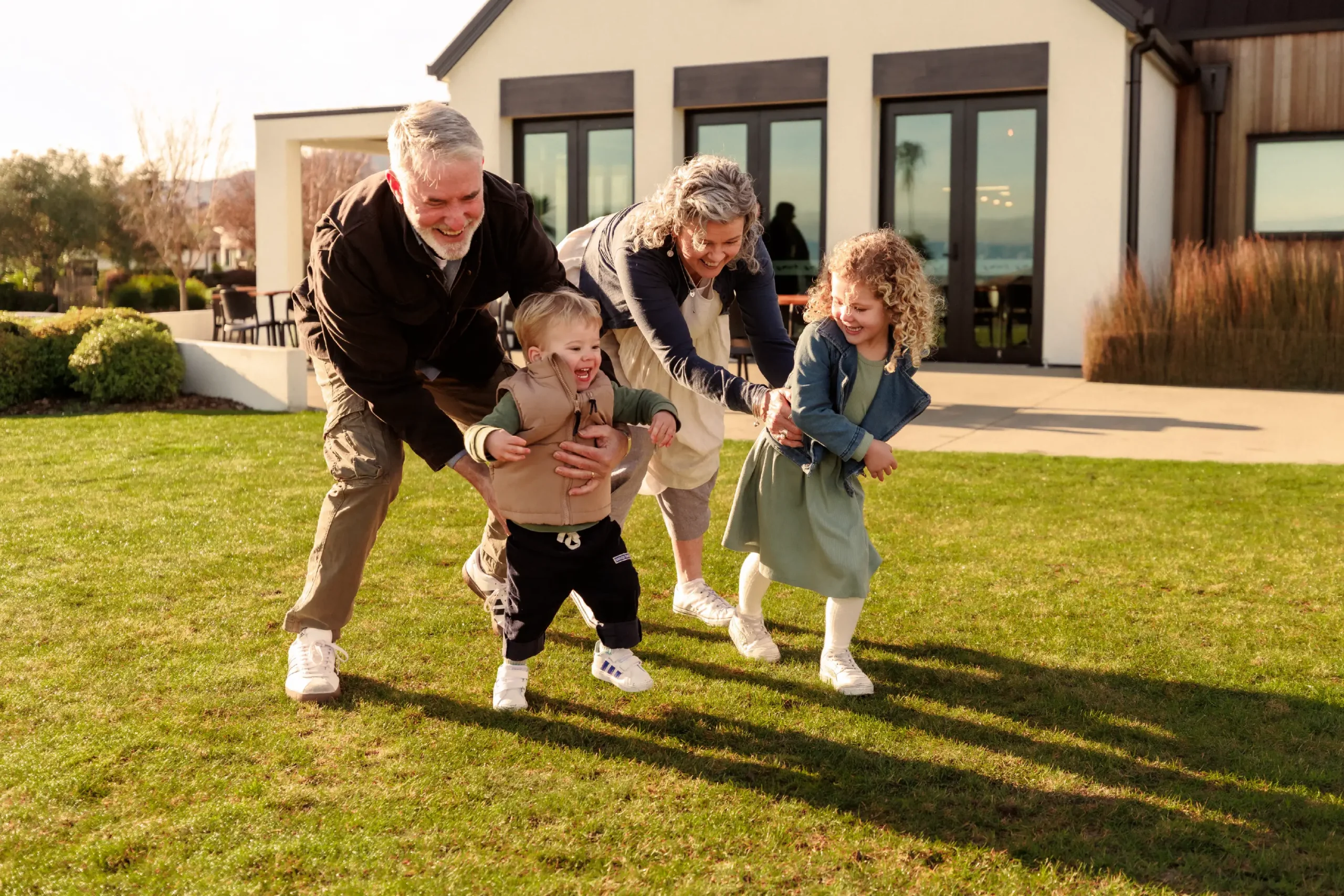 Grandparents playing outdoors on the lawn with their young grandchildren at Olive Estate Lifestyle Village.