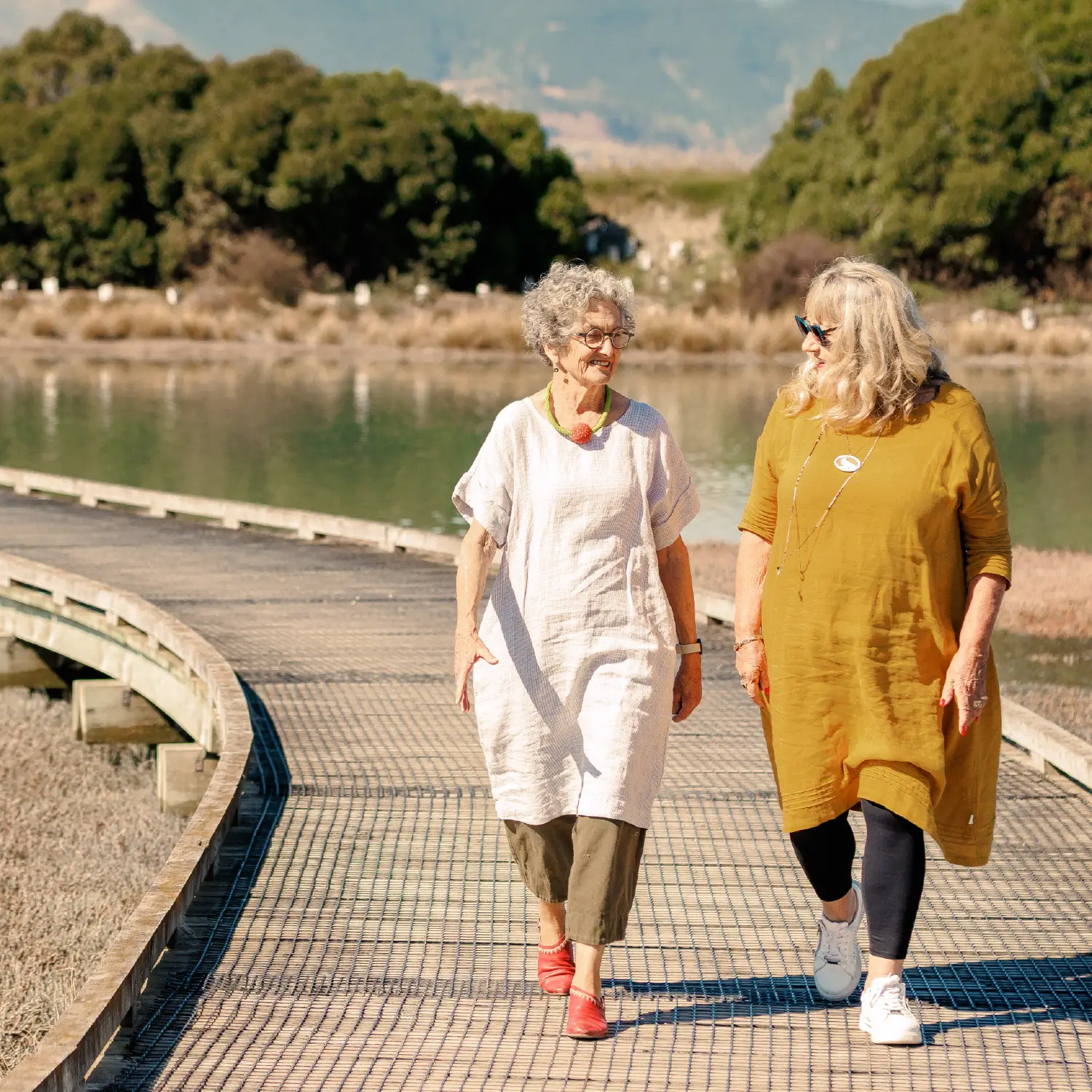Two older women walking along a wooden boardwalk on the Great Taste Trail near Olive Estate Lifestyle Village.