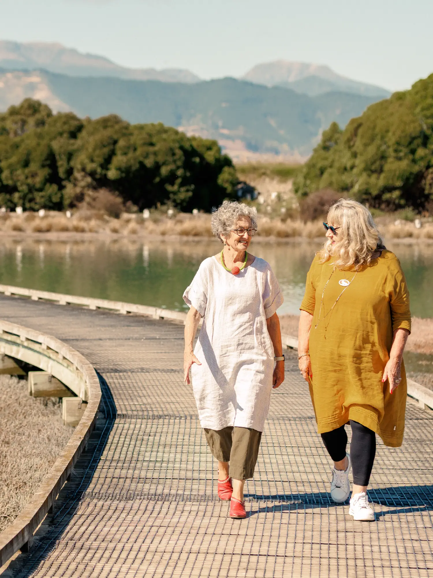 Two older women walking along a wooden boardwalk on the Great Taste Trail near Olive Estate Lifestyle Village.