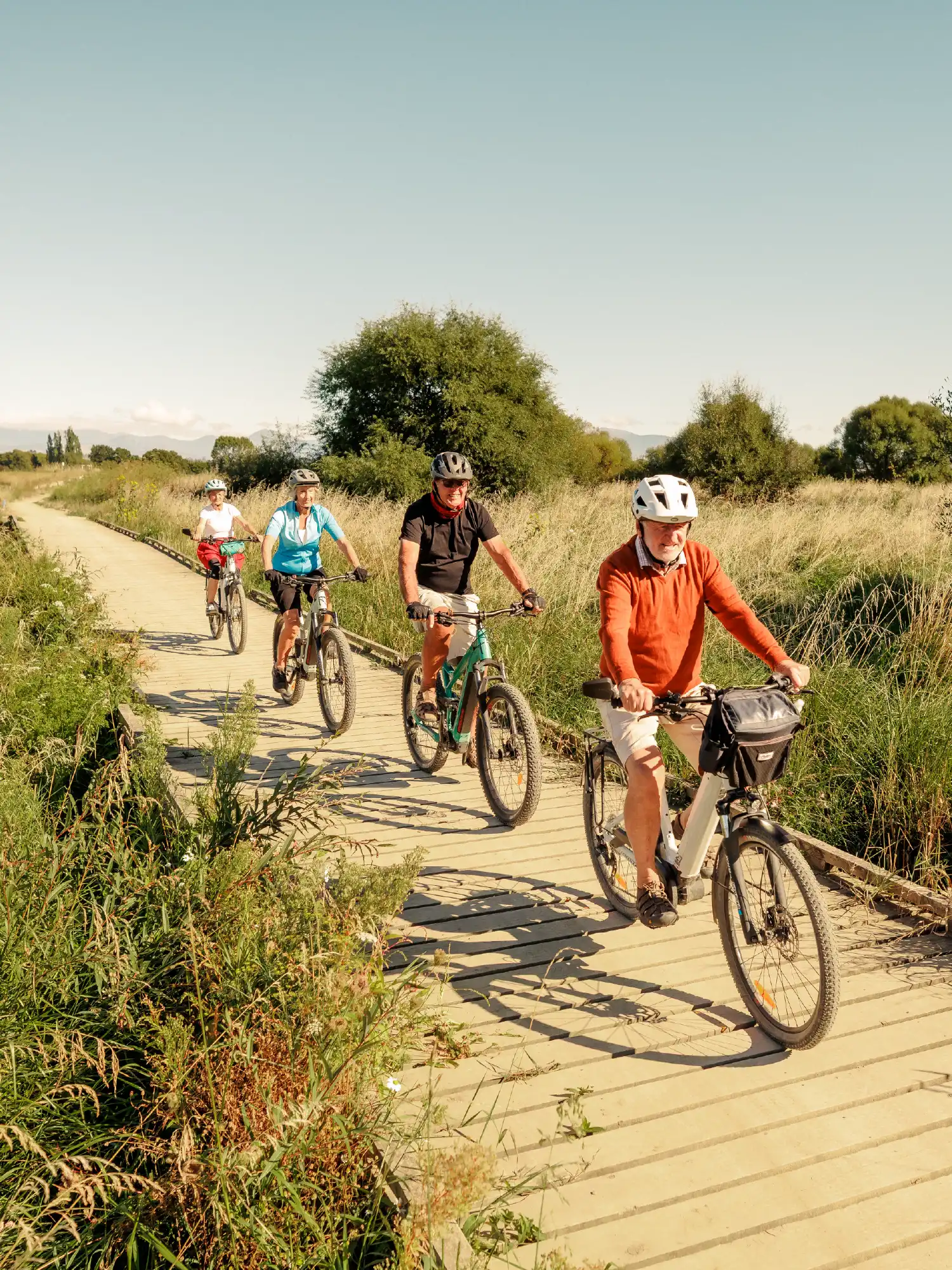 Group of cyclists riding along a wooden boardwalk on the Great Taste Trail near Olive Estate Lifestyle Village.